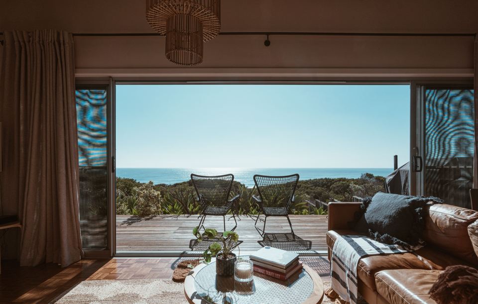 Salon ouvert sur une terrasse de bois, la mer au fond