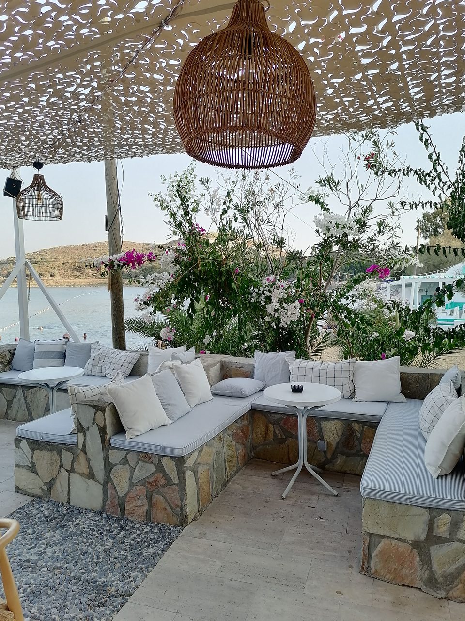 Banquettes maçonnées à coussins sous une canisse, au bord de la mer