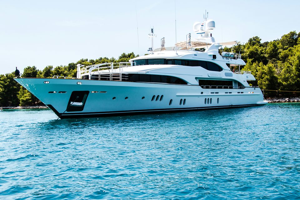 Yacht blanc au mouillage le long d’une côte boisée