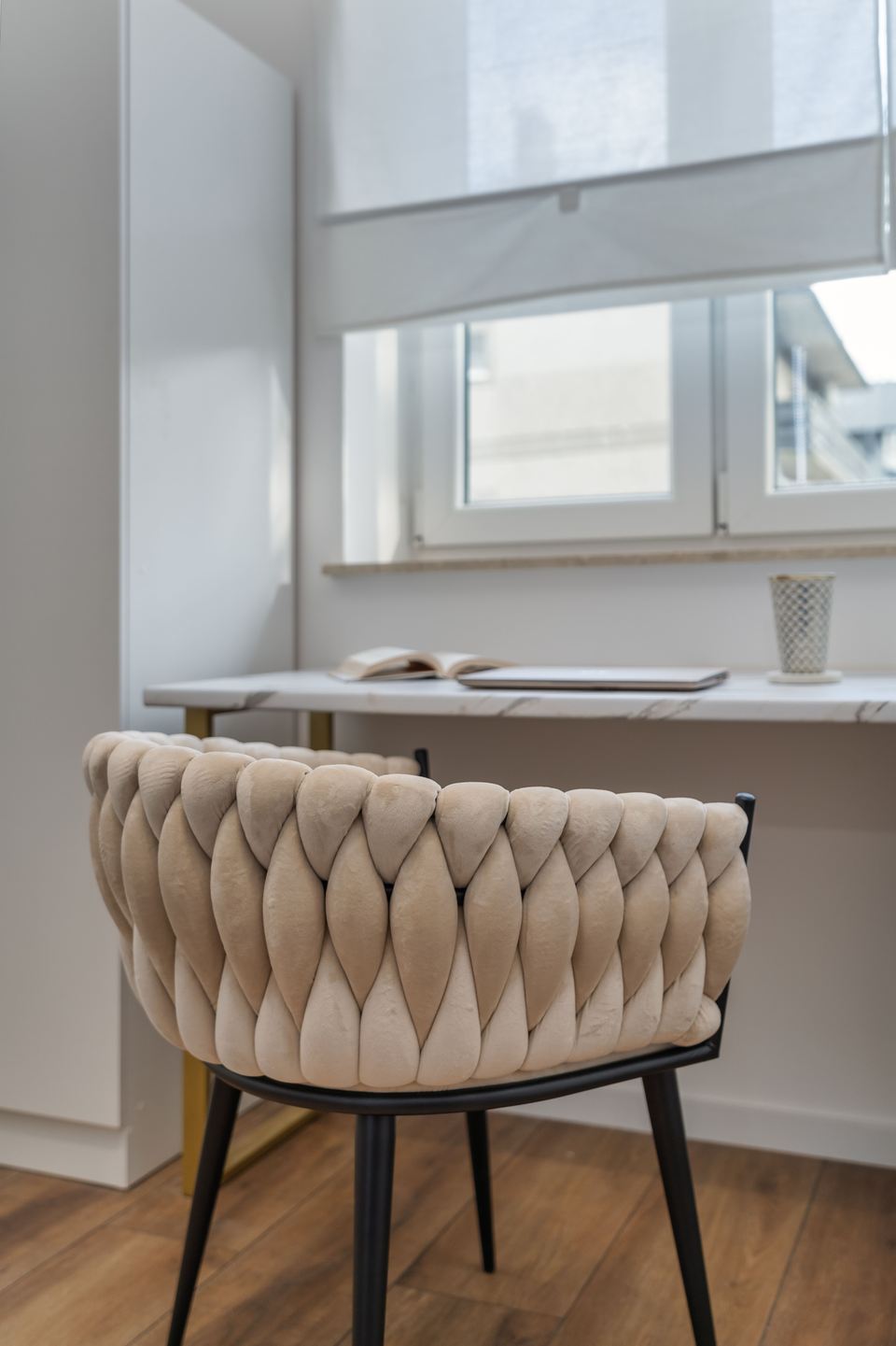 Fauteuil tapissé de tresses écrues devant un bureau blanc, sous la fenêtre