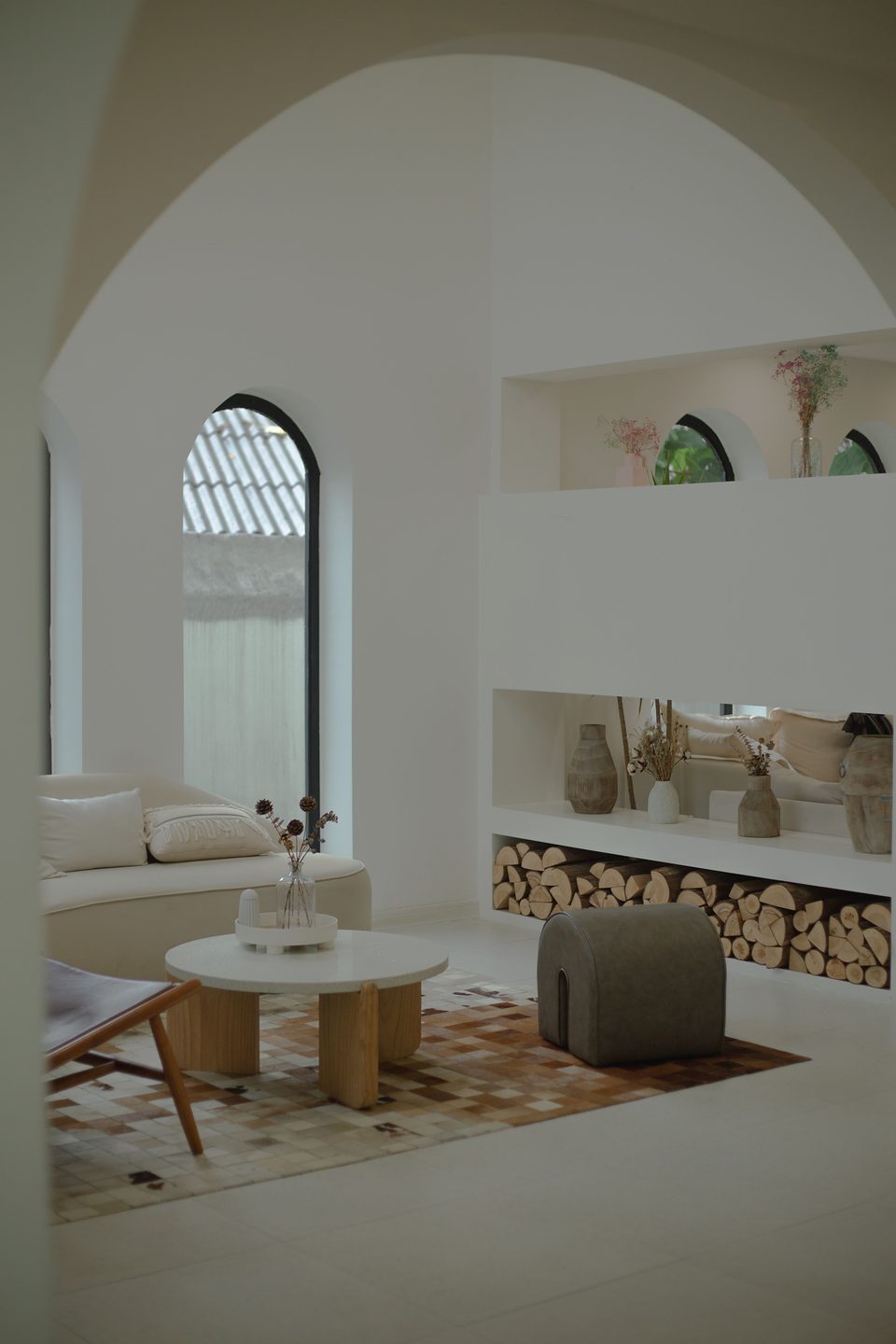 Salon blanc sous des arches, canapé et tapis clairs