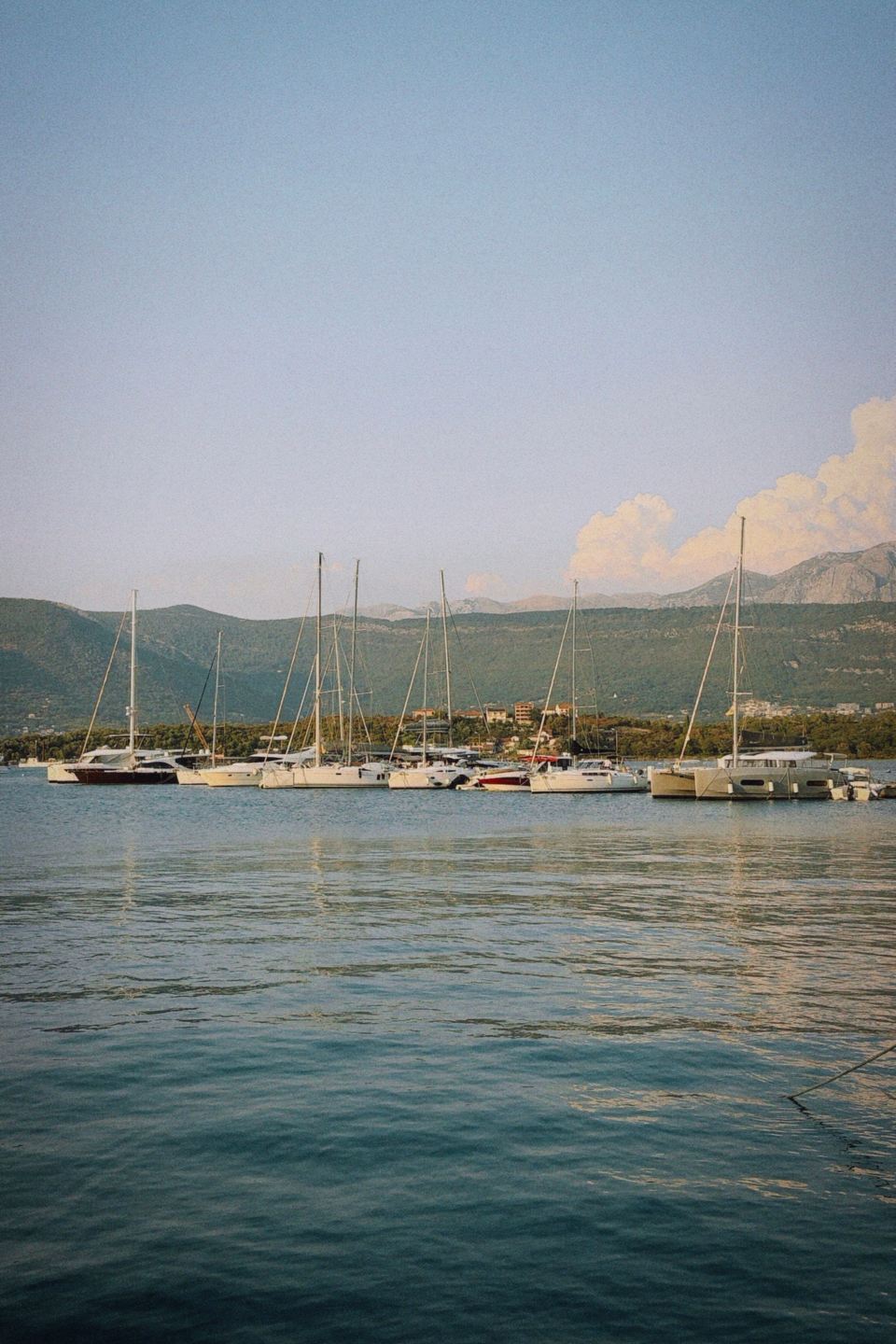Voiliers au mouillage dans une baie calme, montagnes au fond