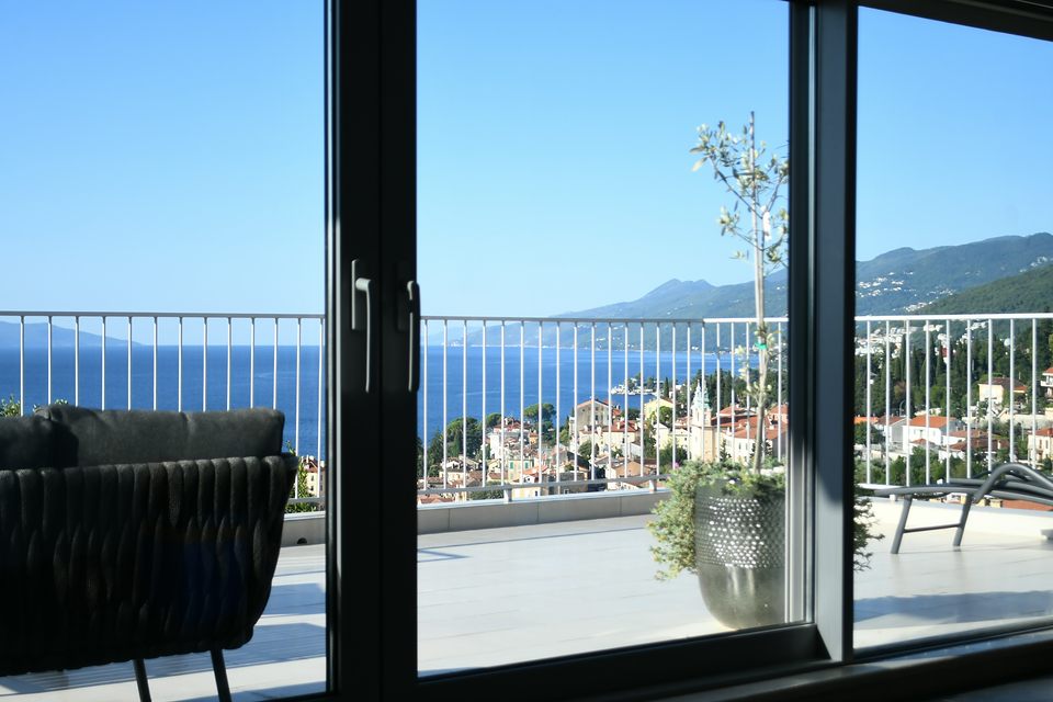 Baie vitrée coulissante ouverte sur une terrasse, la mer au fond